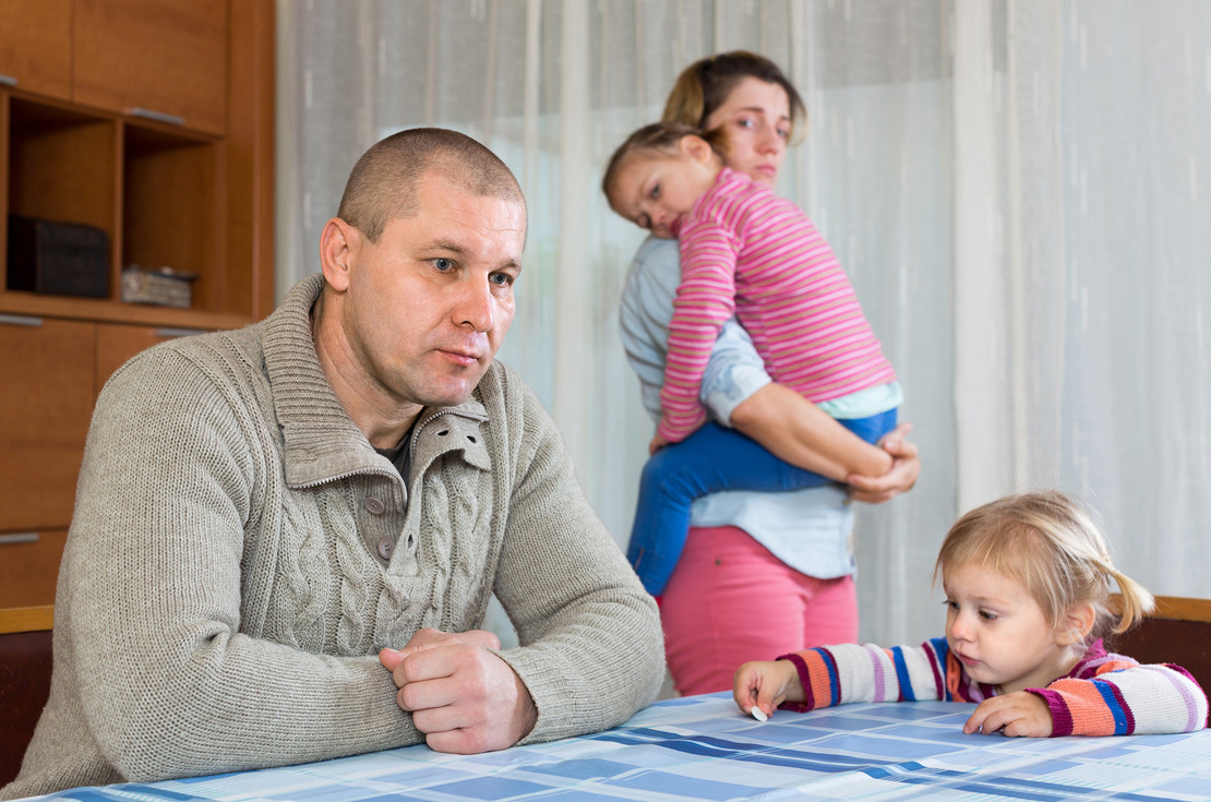 Verzweifelte Eltern mit ihren Kindern in einer Wohnung. 