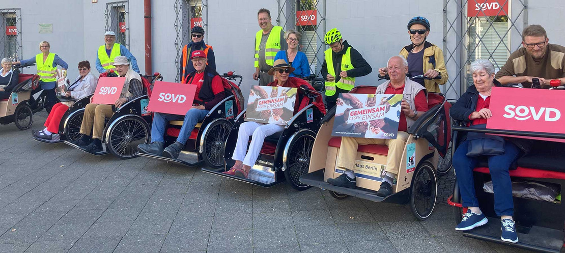 Mehrere Personen in Fahrradwagen mit SoVD-Schildern.