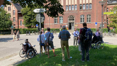 Menschengruppe vor einem Gebäude. 