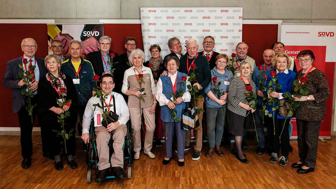 Menschengruppe vor SoVD-Aufstellern. 