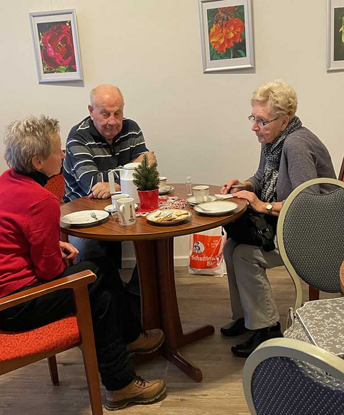 Drei Personn sitzen an einem Tisch und unterhalten sich. 