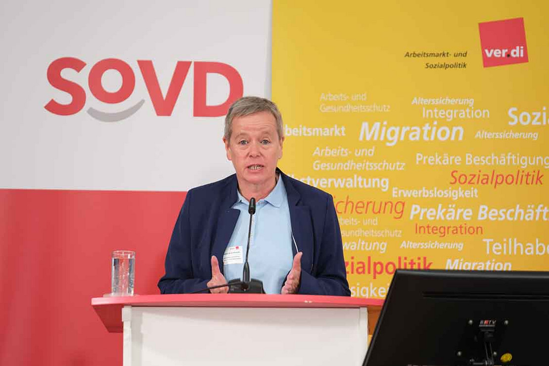 Frau spricht vor großem SoVD-Logo