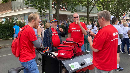 Menschen in roten SoVD-Shirts essen etwas. 