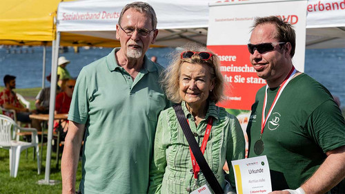 Drei Menschen vor einem SoVD-Aufsteller. 